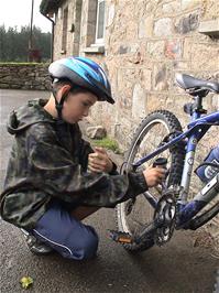 Harry oils his chain with Michael's cycle oil outside Bellever Youth Hostel