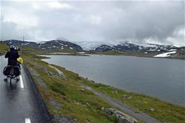 Fantesteinsvatnet and the road to Fantesteinen. Norway's highest mountain Galdhøppigen is in the clouds beyond