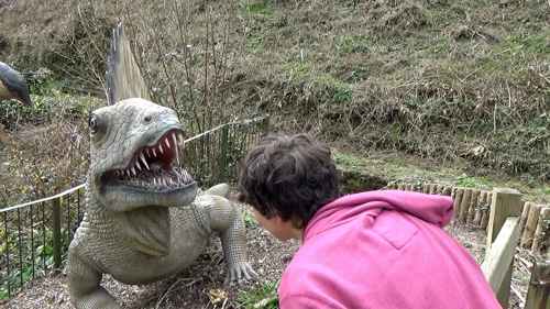 Lawrence befriends a small, ferocious-looking dinosaur in Dinosaur Grove, Wookey Hole.